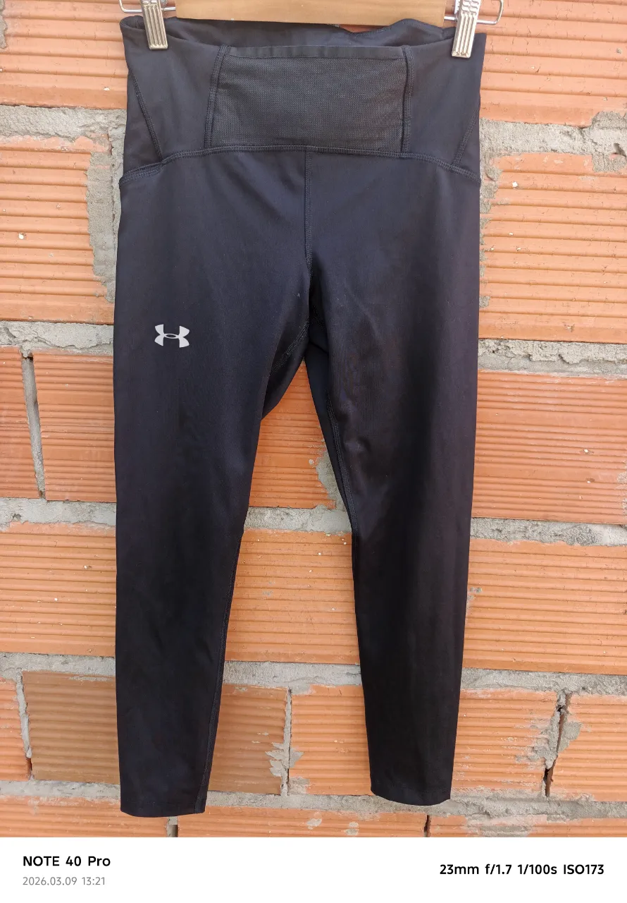 Calzas deportivas negras de entrenamiento, ideales para running o gimnasio. Poseen detalles de microperforados en las piernas para mayor transpiración y un bolsillo oculto en la cintura.