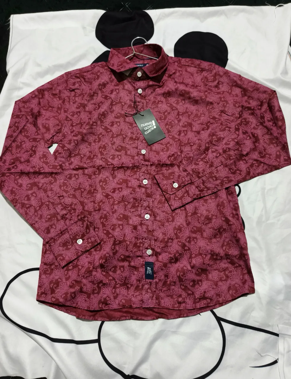 Camisa de manga larga con estampa floral en tonos de rojo y rosa. Posee cuello clásico y botones al frente.