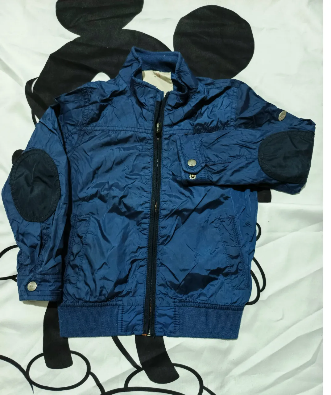 Campera bomber azul para niño, con detalles en los codos y puños elastizados. Ideal para entretiempo o días frescos.