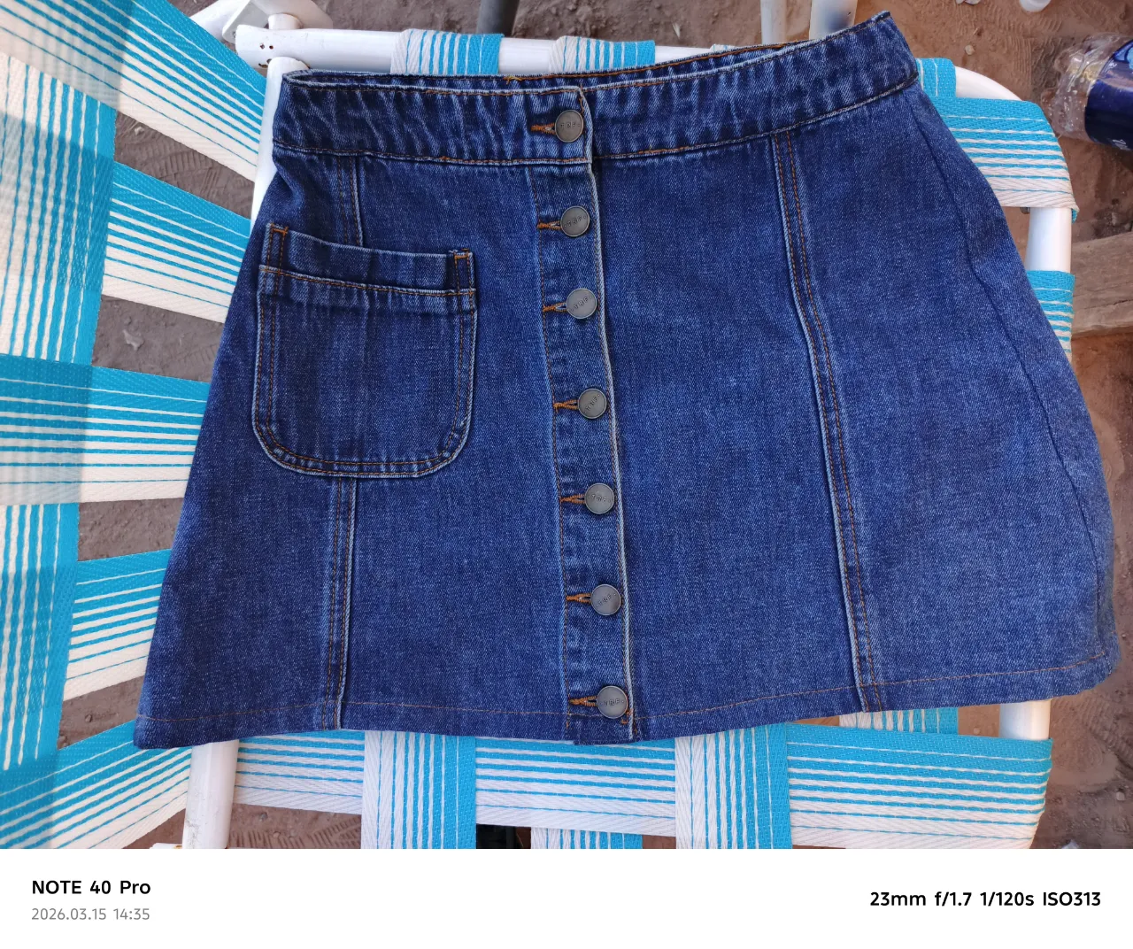 Pollera de jean azul con botones al frente y bolsillo lateral.