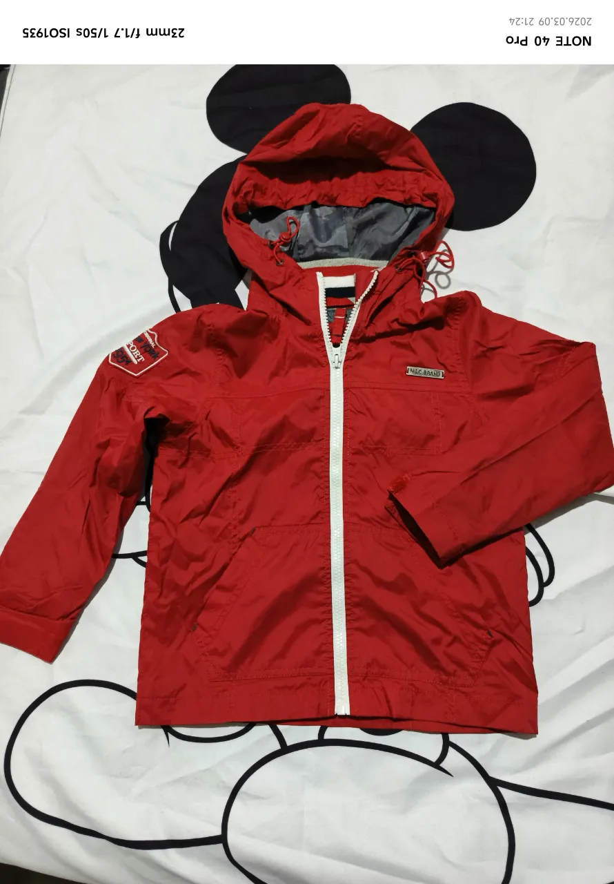 Campera impermeable roja con capucha, ideal para los días de lluvia o viento. Posee cierre al frente y bolsillos laterales. Perfecta para actividades al aire libre o para el uso diario.