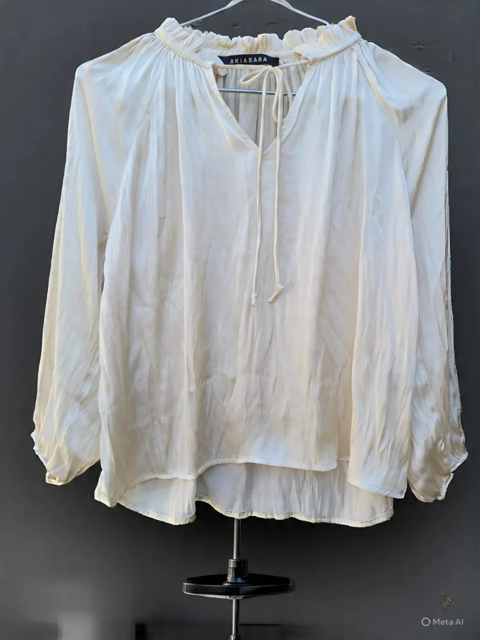 Blusa de seda color crudo con mangas largas y escote en V con lazo. Detalle de volados en el cuello y puños ajustados con lazo. Ideal para un look elegante y bohemio.