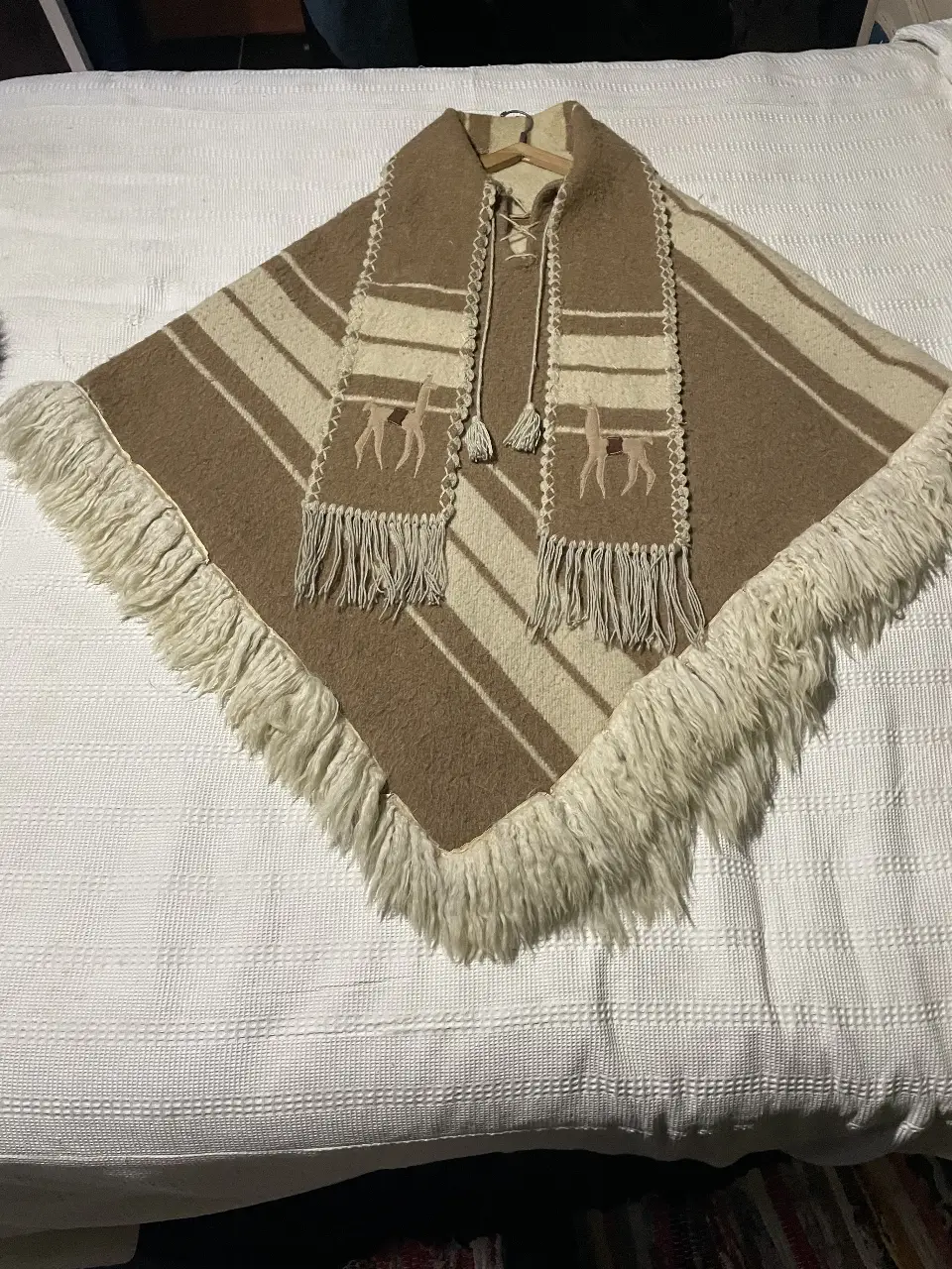Poncho artesanal de lana con diseño a rayas en tonos marrones y blanco. Incluye bufanda a juego con detalles de bordado y flecos.