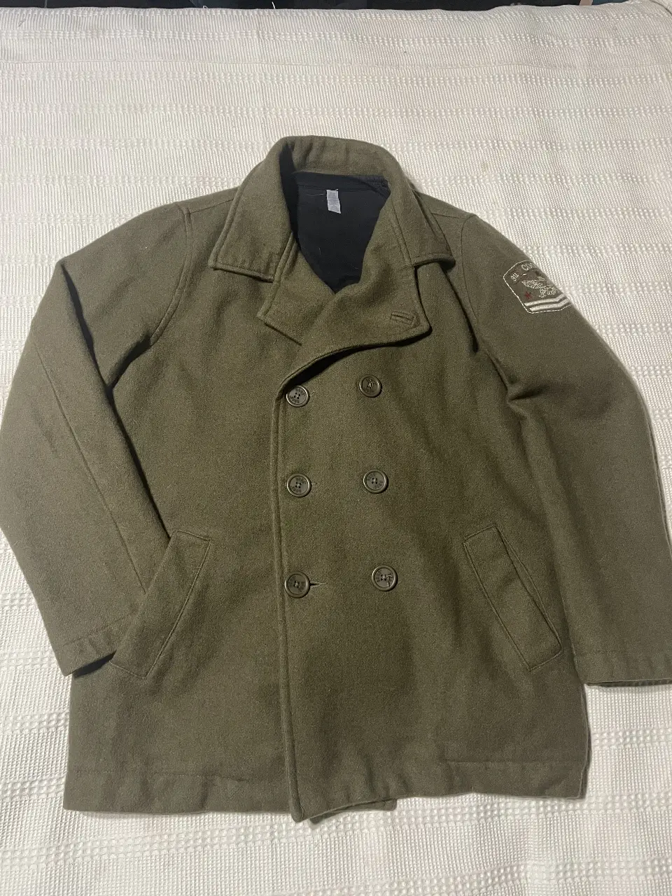 Tapado de paño verde oscuro con botones y bolsillos. Estilo militar, ideal para el invierno.