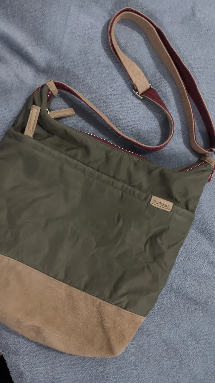 Amplio bolso cruzado color verde militar con base de gamuza color tiza. Posee correa ajustable gamuzada. Un cierre principal impeclabe y bolsillo externo. Su forro por dentro sin detalles y bolsillo i nterno con cierre.