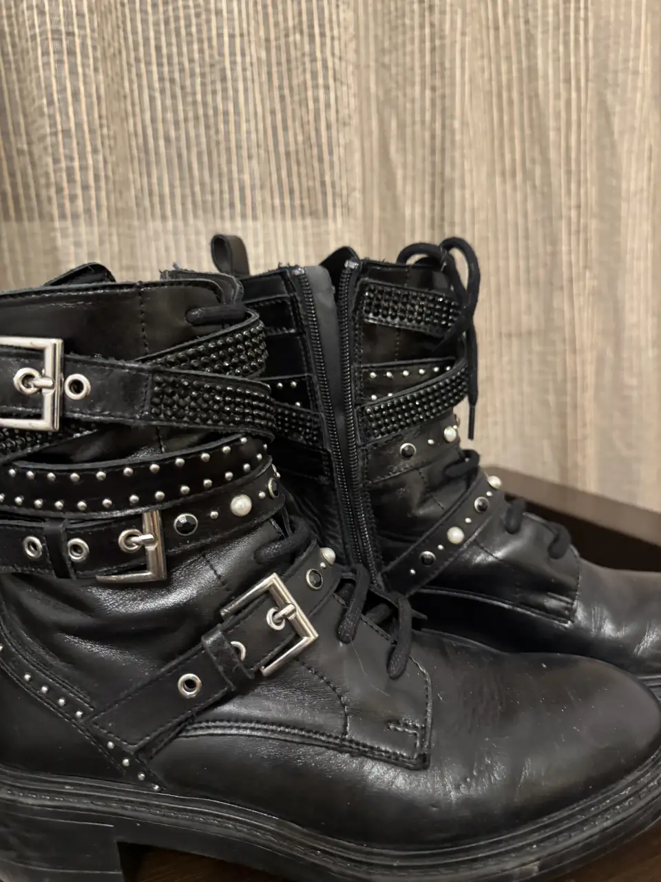Botines negros de cuero con detalles de tachas y hebillas. Tienen cierre lateral y cordones. Marca Zara.