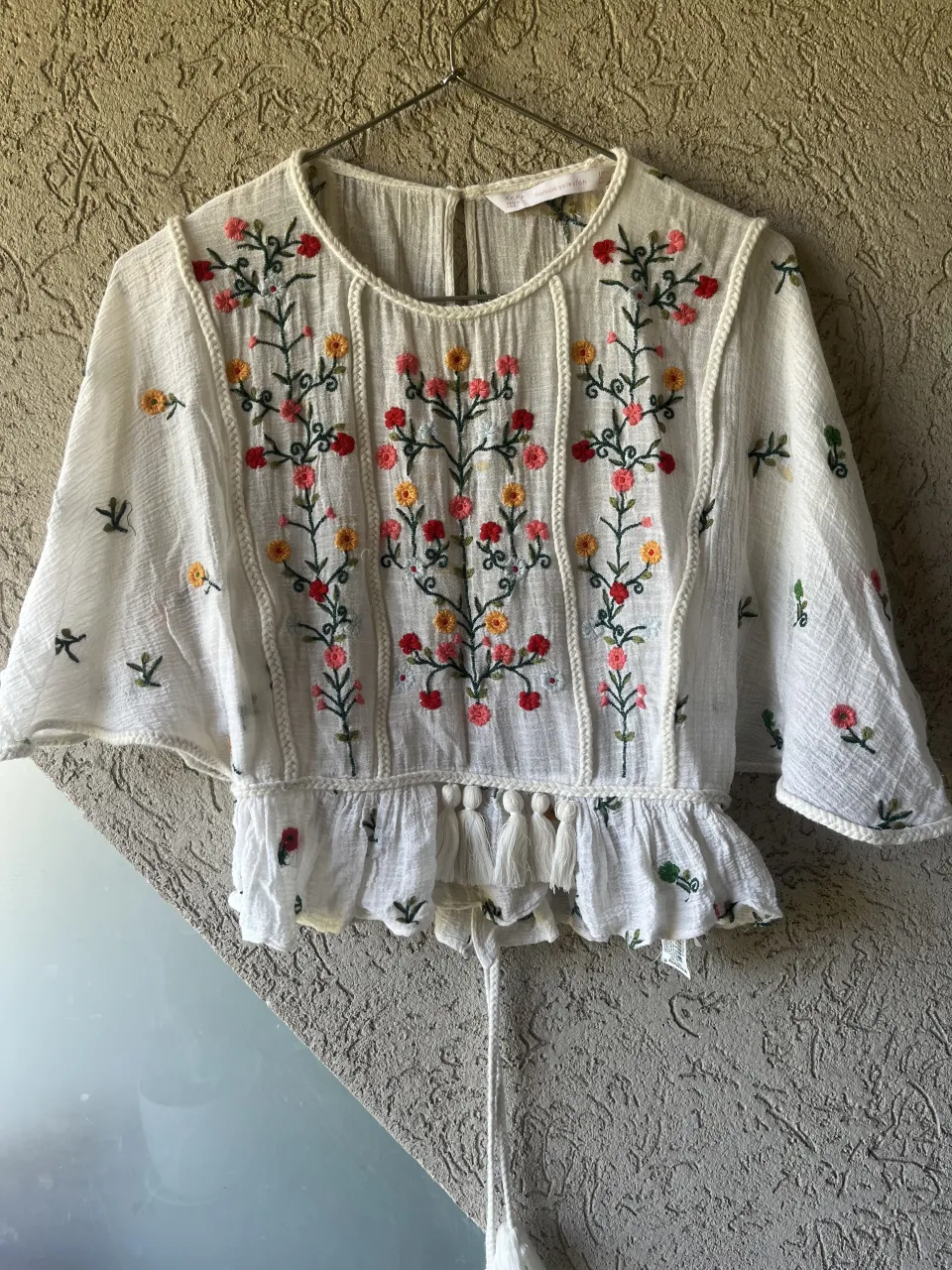 Blusa ZARA blanca con bordados florales en el frente y mangas.  Las mangas son cortas y amplias. En la espalda tiene un lazo para ajustar.