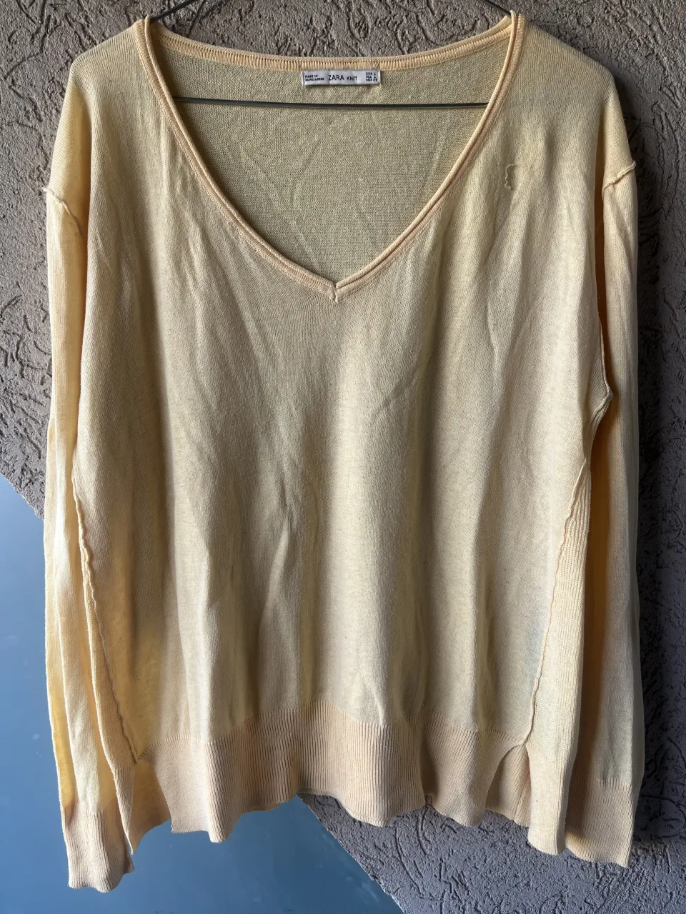 Sweater ZARA de hilo color amarillo pastel, con escote en V y mangas largas.  Ideal para un look casual y cómodo.