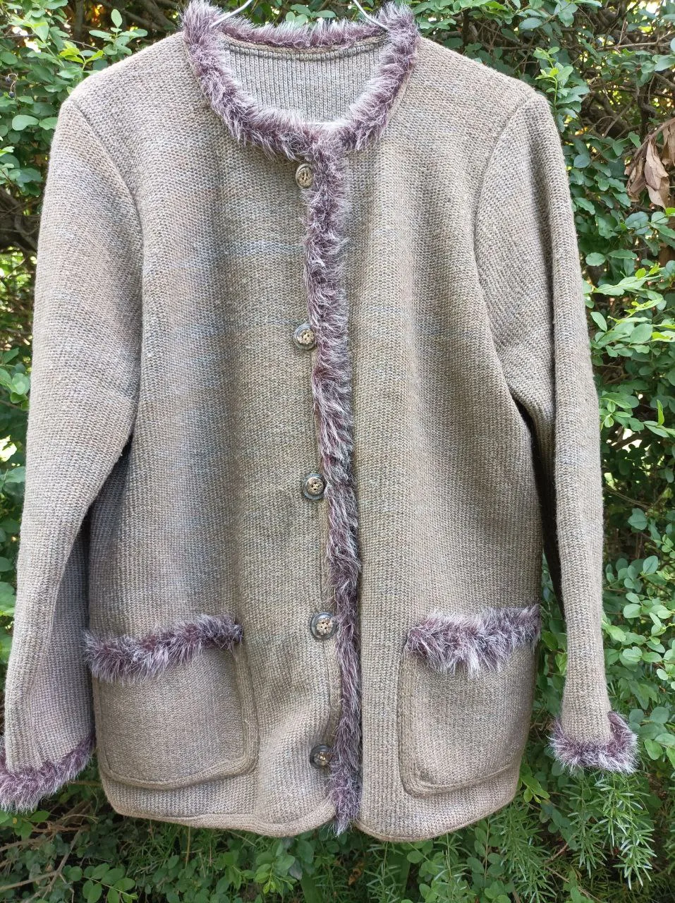 Cardigan de lana tejido con detalles de pelo sintético en cuello, puños y bolsillos. Posee botones al frente y un diseño clásico y elegante.