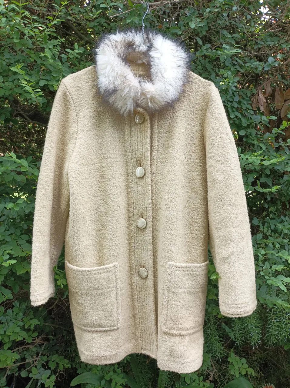 Abrigo de paño color beige con cuello de piel sintética desmontable. Posee botones al frente y dos bolsillos amplios. Ideal para un look elegante y abrigado.