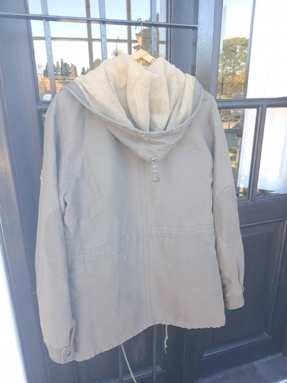 Campera parka verde militar con capucha forrada en piel sintética. Ideal para el invierno, con bolsillos y ajuste en la cintura. Talle M.