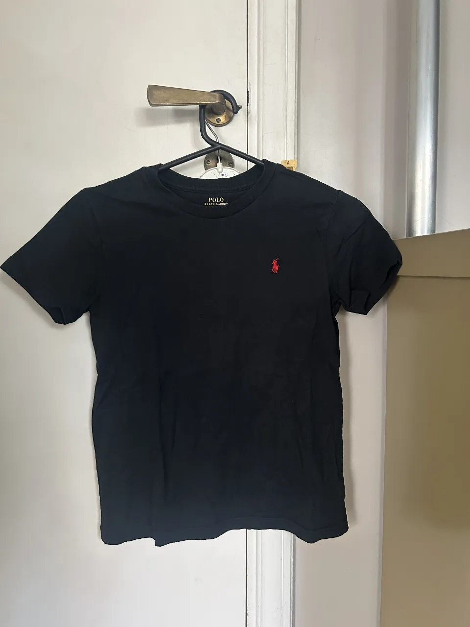 Remera negra de hombre, de algodón, con el logo de Polo Ralph Lauren en rojo. Ideal para un look casual y cómodo.
