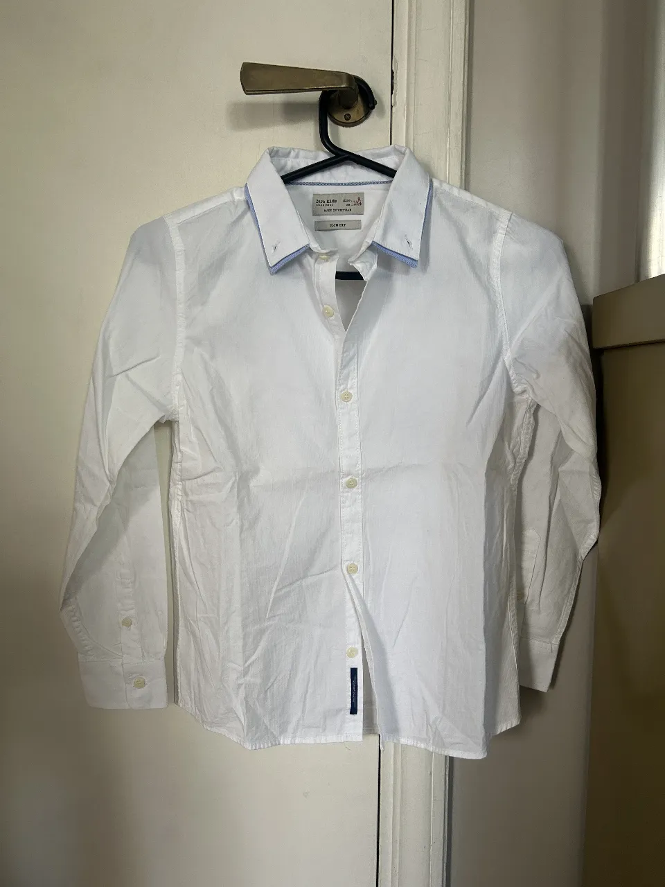 Camisa blanca de manga larga para niño, con detalles en celeste en el cuello. Marca Zara Kids, talle 9.