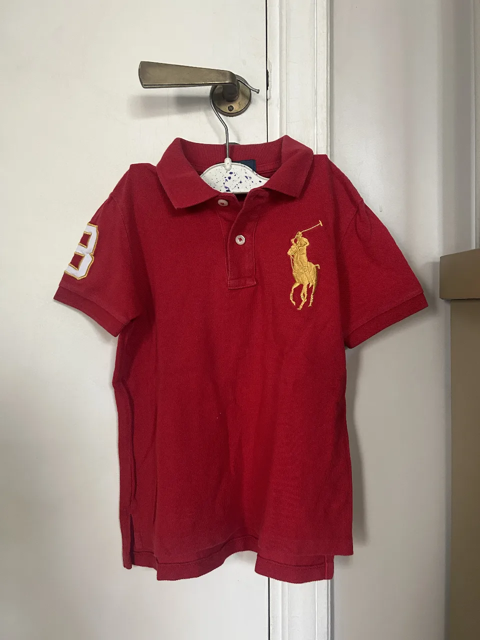 Remera polo roja de niño, con el número 3 y el logo del jugador de polo en amarillo. Ideal para un look casual y deportivo.