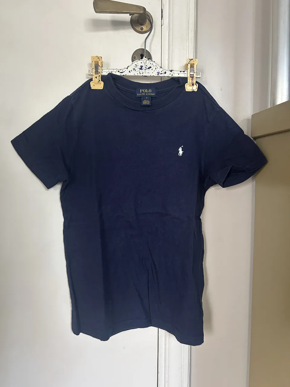 Remera Polo Ralph Lauren azul marino para niño, talle 7. Con el icónico logo del jugador de polo bordado en blanco. Ideal para un look casual y cómodo.