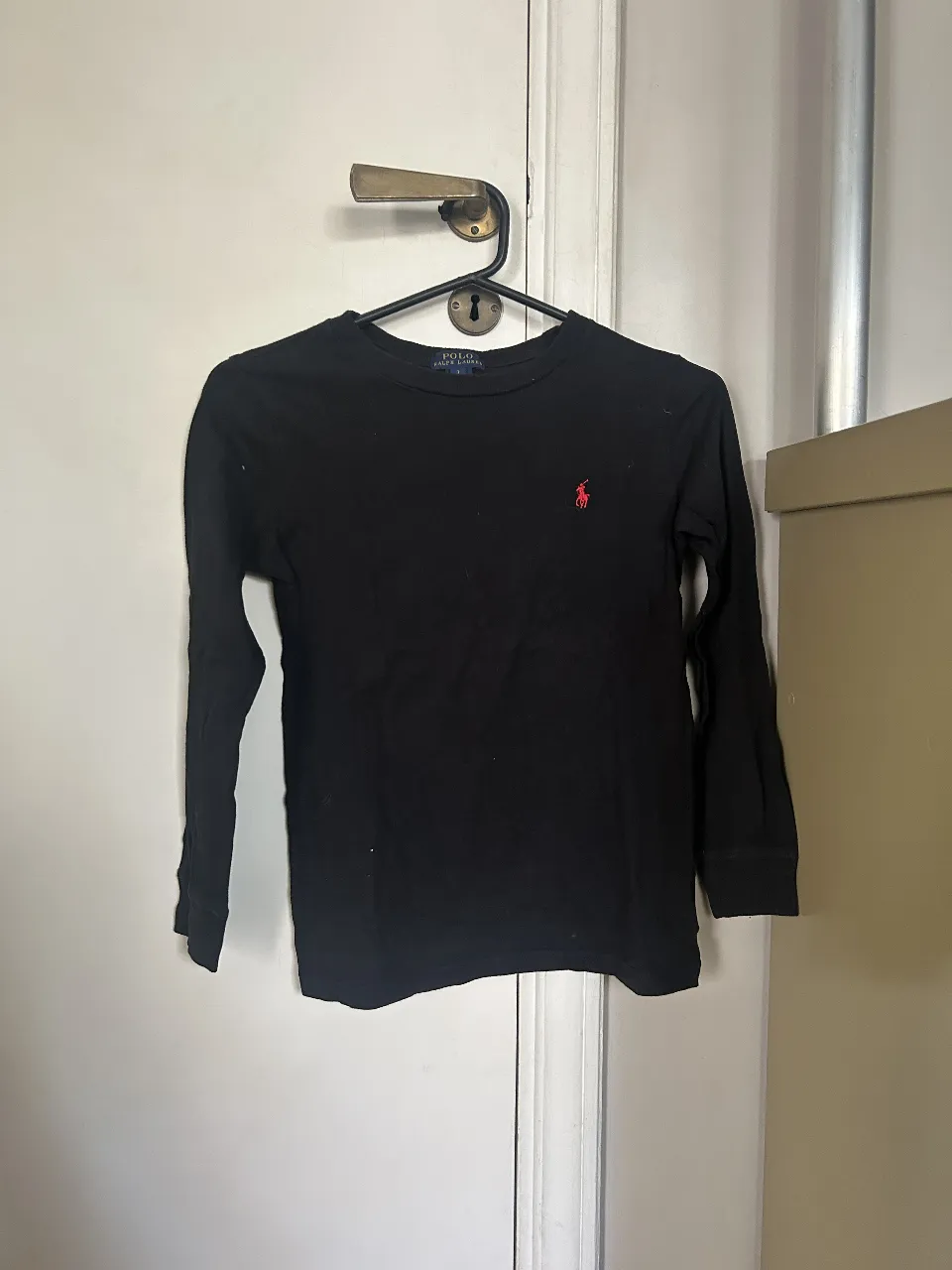 Remera manga larga negra de algodón, con logo bordado en rojo. Ideal para un look casual y cómodo.