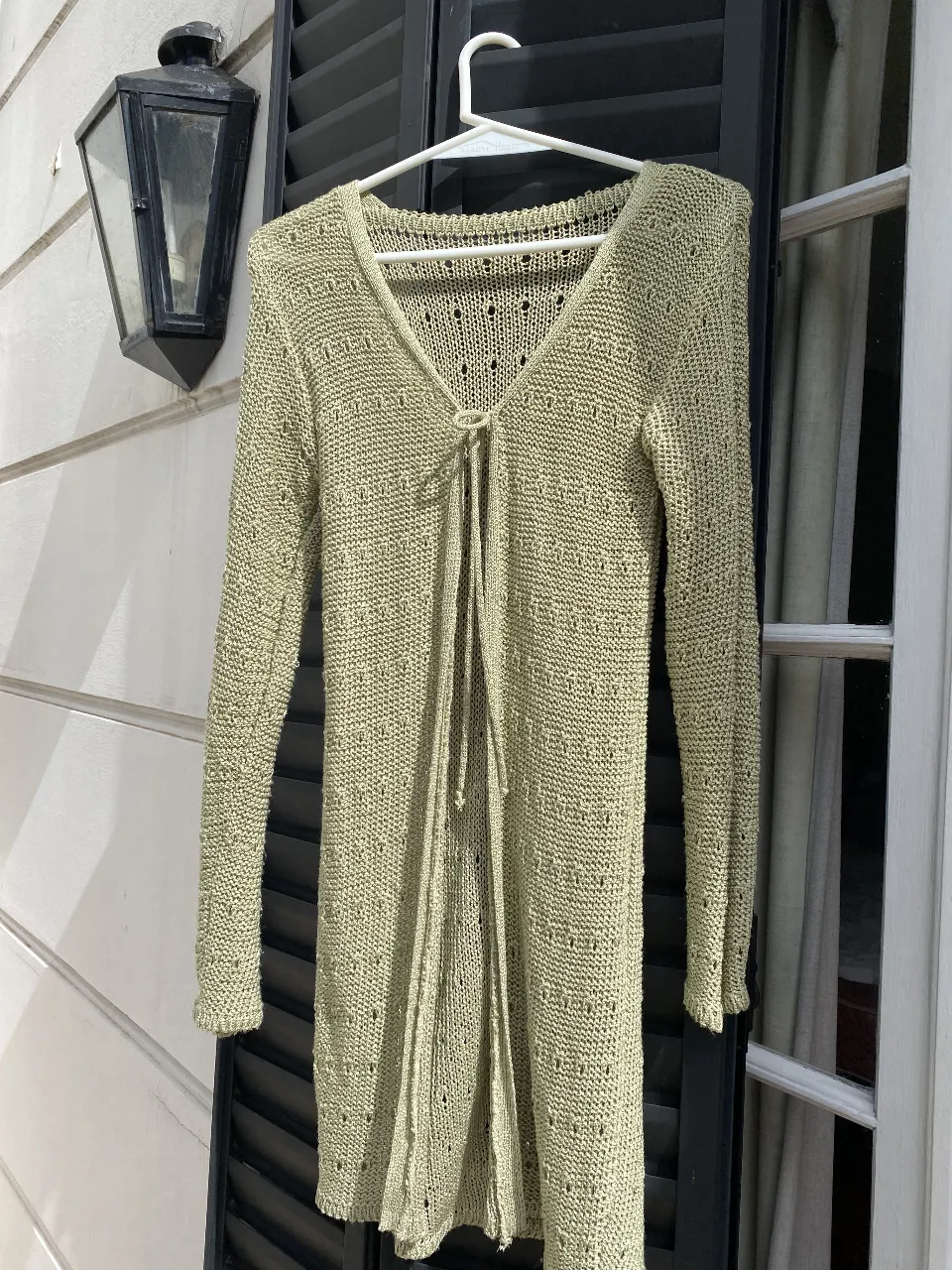 Cardigan largo tipo “spolverino” tejido en color verde claro, con escote en V y detalle de lazo. Ideal para un look casual y cómodo.