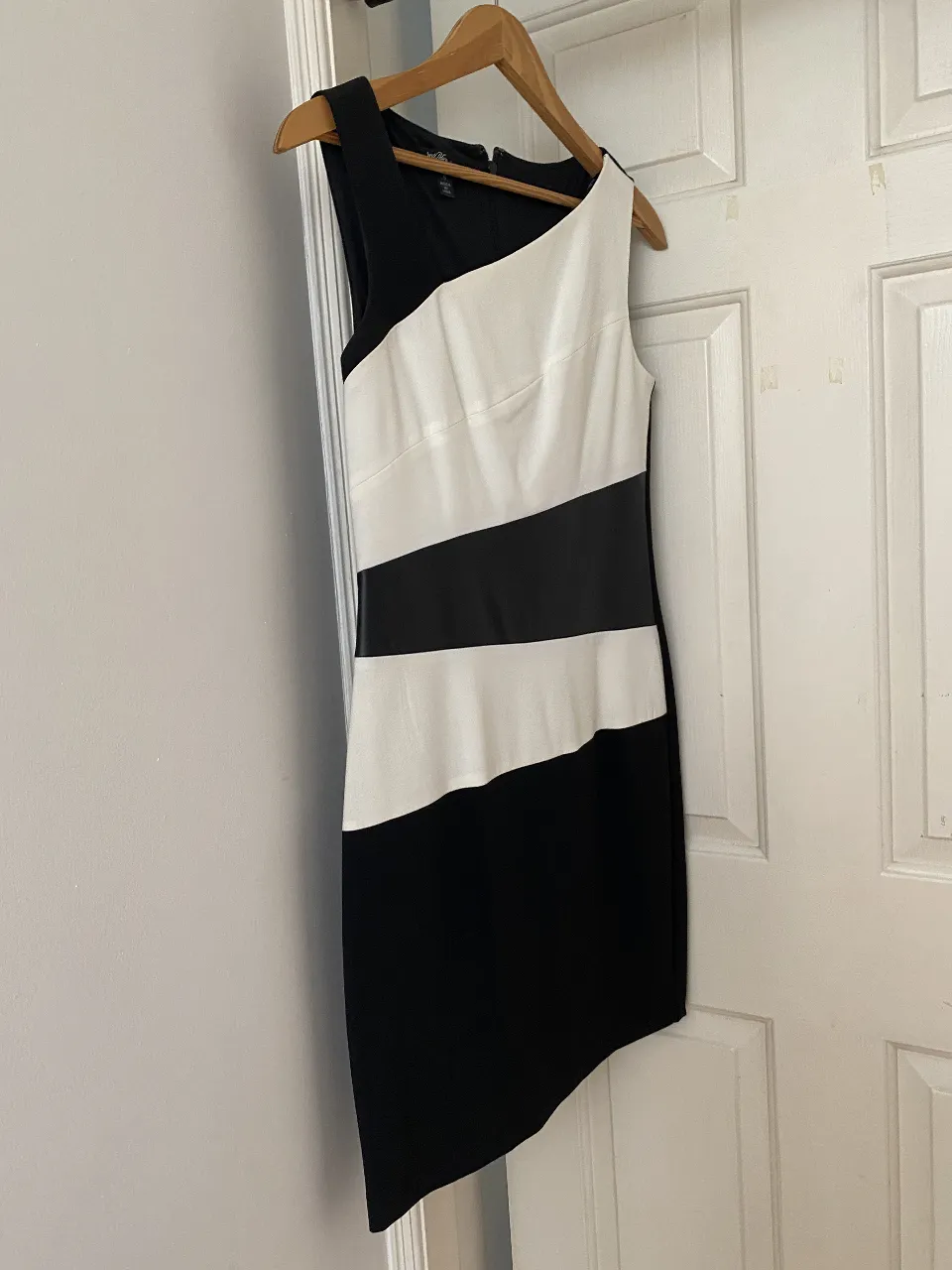 Vestido midi asimétrico en blanco y negro. Diseño moderno y detalle diagonal. Ideal para eventos formales o salidas nocturnas.