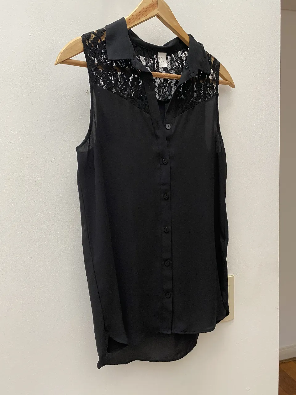 Blusa canisa negra con detalle de encaje en el frente y cuello. Ideal para un look elegante y sofisticado.