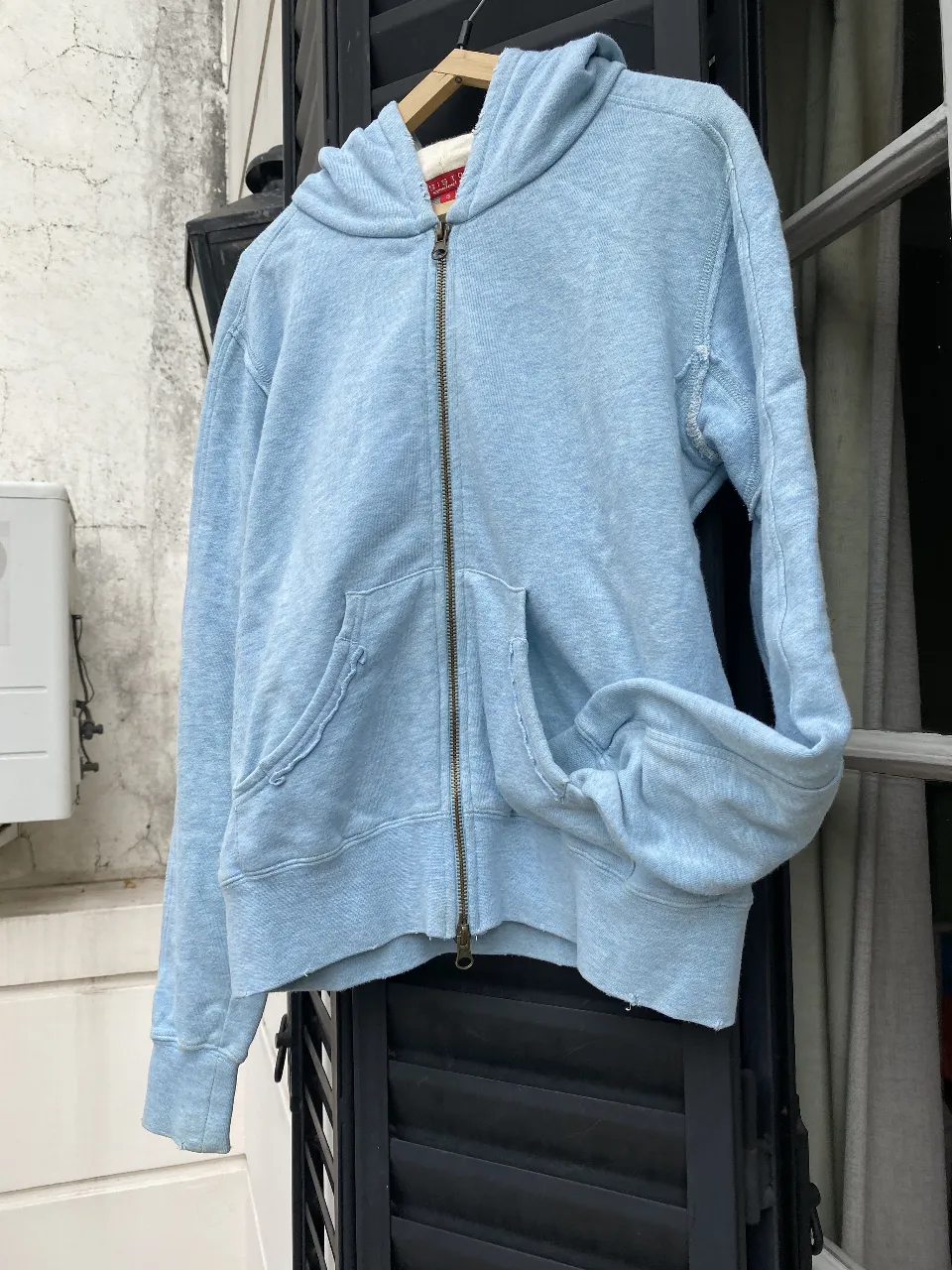 Buzo con cierre de algodón celeste, con capucha bordada lentejuelas y bolsillos delanteros. Ideal para un look casual y cómodo.