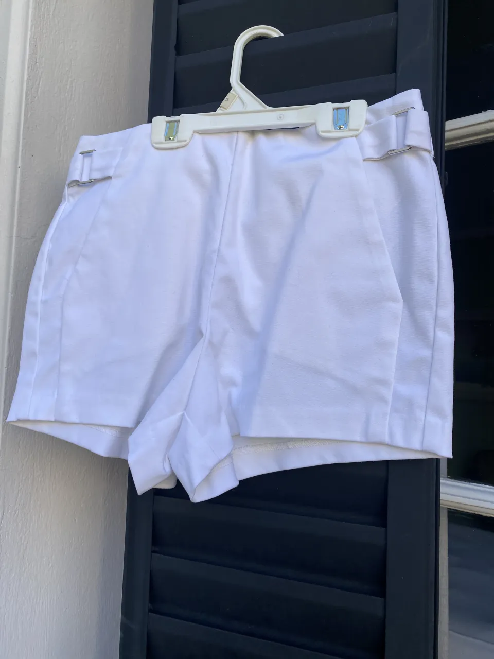 Shorts blancos con detalles metálicos en la cintura, bolsillos en el frente y traseros.