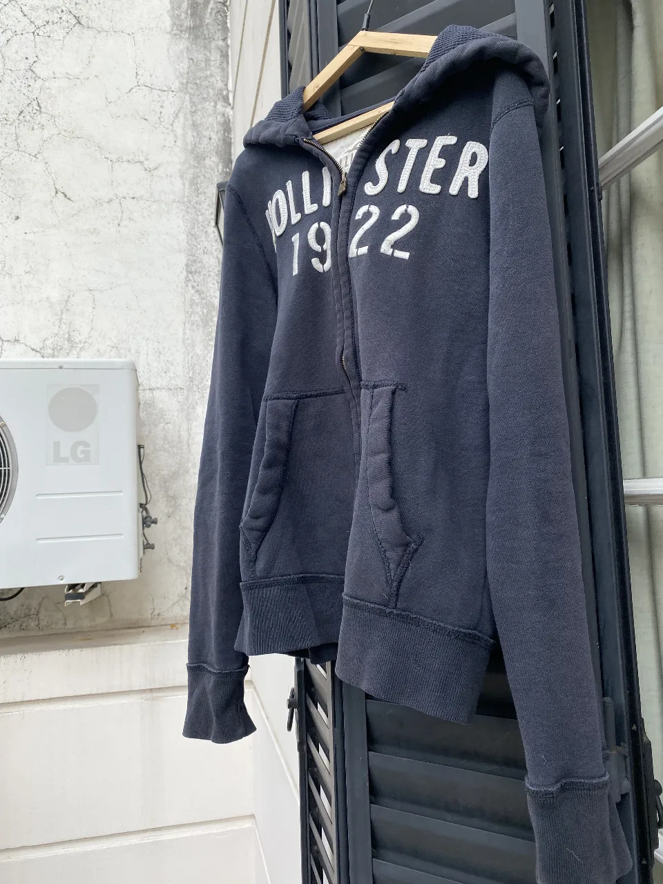 Buzo con cierre Hollister 1922, negro con letras blancas. Ideal para un look casual y abrigado.