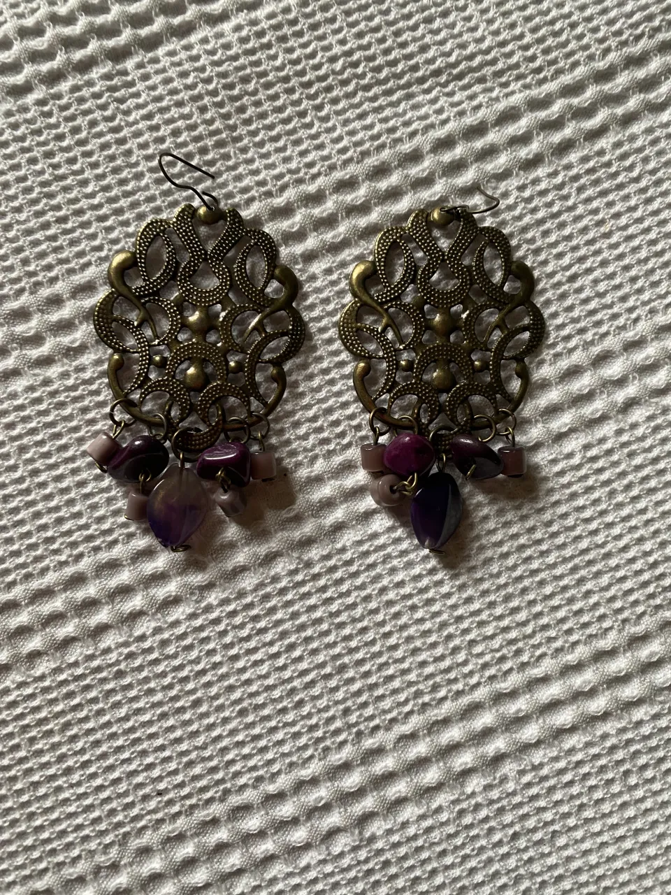 Aros colgantes con diseño filigrana y detalles en piedras violetas. Un accesorio ideal para darle un toque bohemio y elegante a tu look.