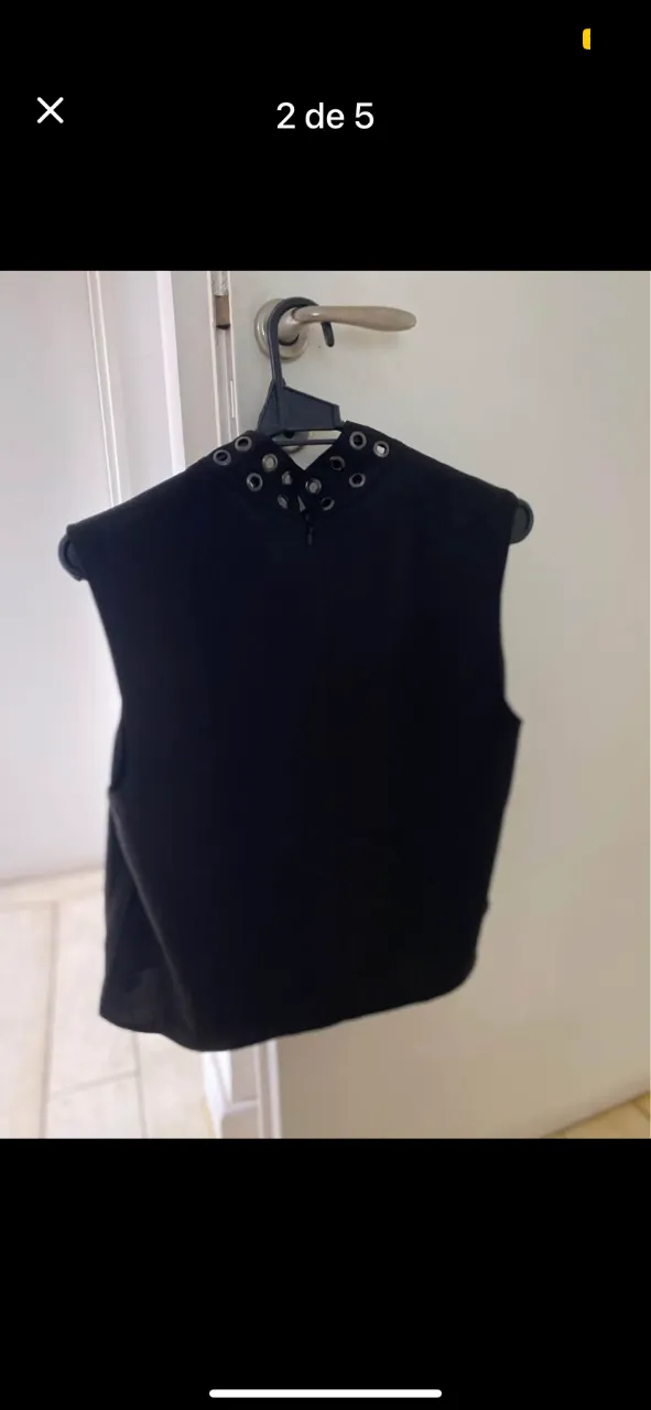 Top negro con cuello alto y detalles de arandelas metálicas. Ideal para un look moderno y audaz.