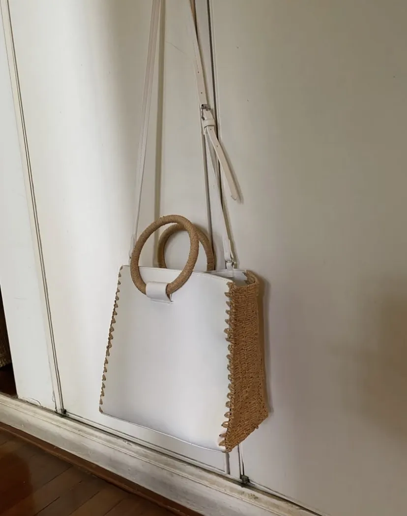 Cartera Zara tipo tote bag blanca con detalles en tejido de rafia y doble correa, de hombro y manijas redondas. Ideal para un look casual y moderno.