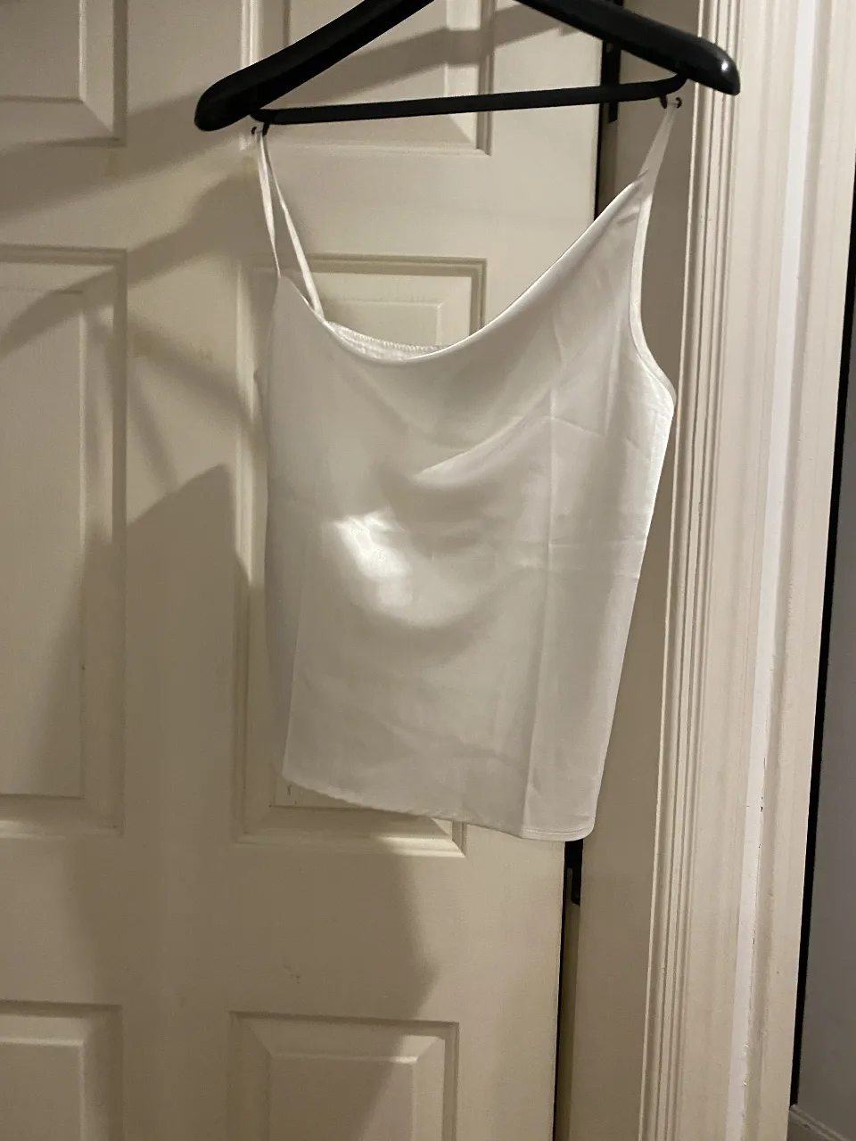 Top blanco de satén con tirantes finos y escote “buche”Ideal para combinar con pantalones de vestir o jeans.