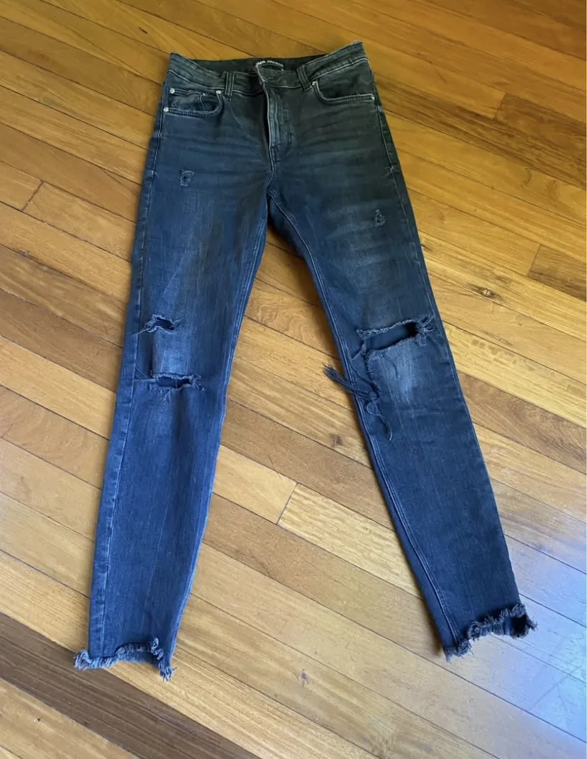 Jeans Zara de mujer, tiro alto, negro con roturas en las rodillas y flecos en el bajo. Ideal para un look casual y moderno.