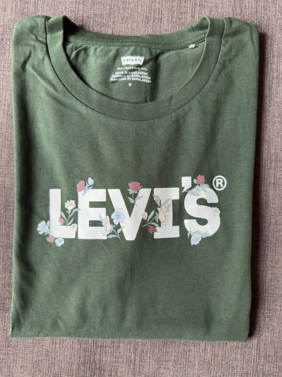 Remera manga corta verde con estampa de flores y el logo de Levi's en blanco.