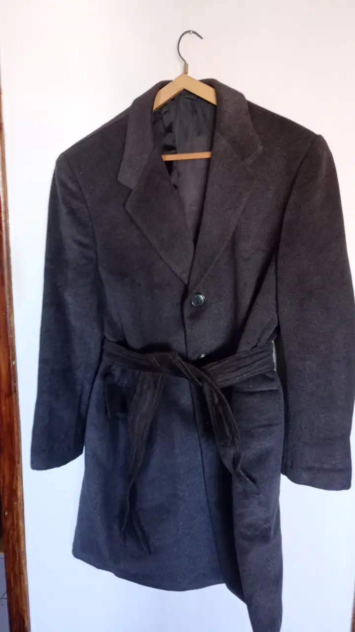 Sobretodo de paño gris oscuro  ( piel de camello)con cinturón. Ideal para el invierno, este tapado de hombre es elegante y versátil. Cuenta con un botón y un cinturón para ajustar la cintura. Perfecto para un look formal o casual. 