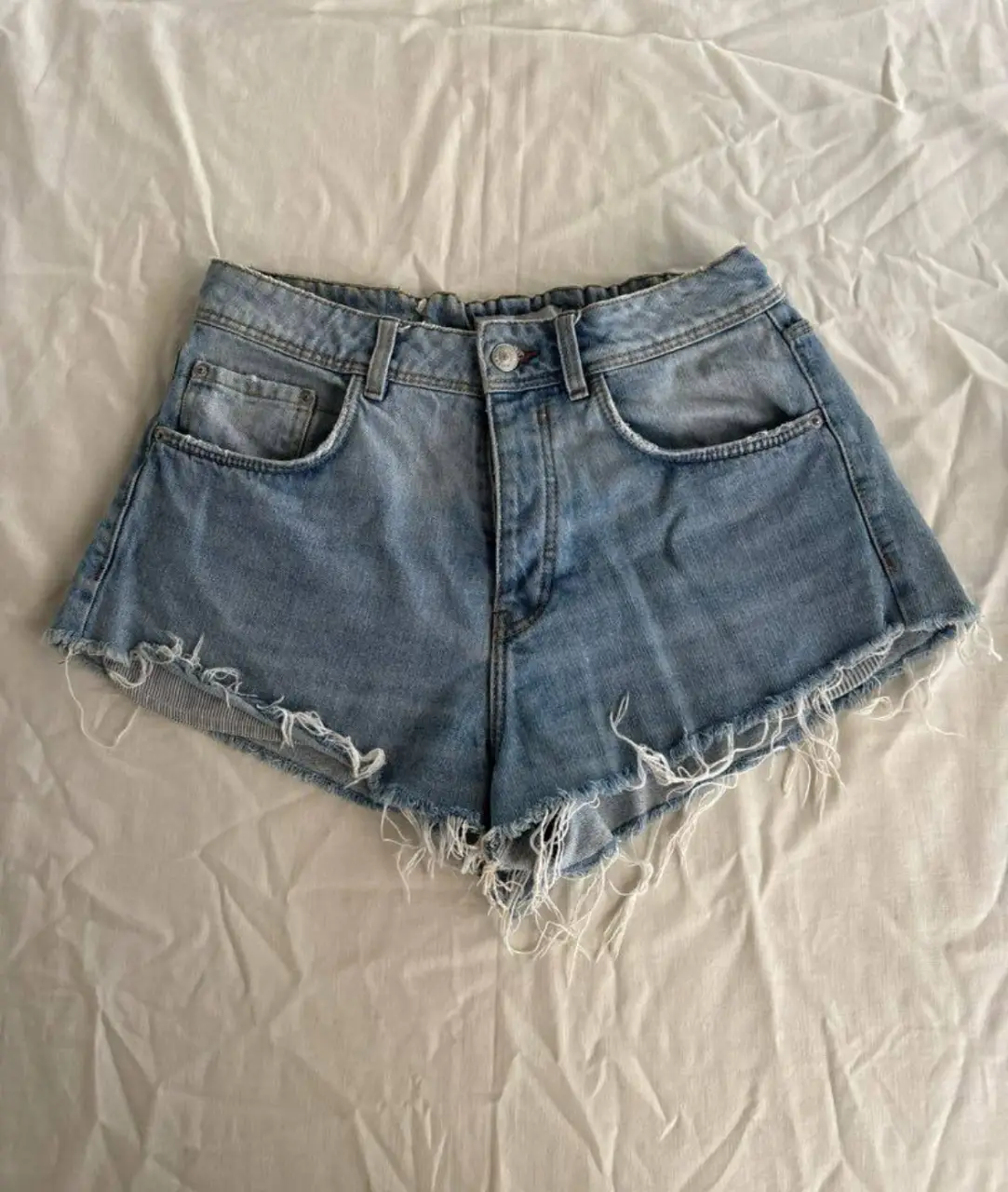 Short de jean de mujer, tiro medio, con detalles desflecados en los bordes. Marca Trafaluc Zara.