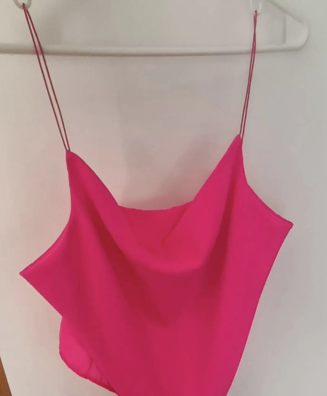 Top rosa vibrante con breteles finos y escote pronunciado. Ideal para un look canchero y a la moda, perfecto para salidas nocturnas o eventos informales.