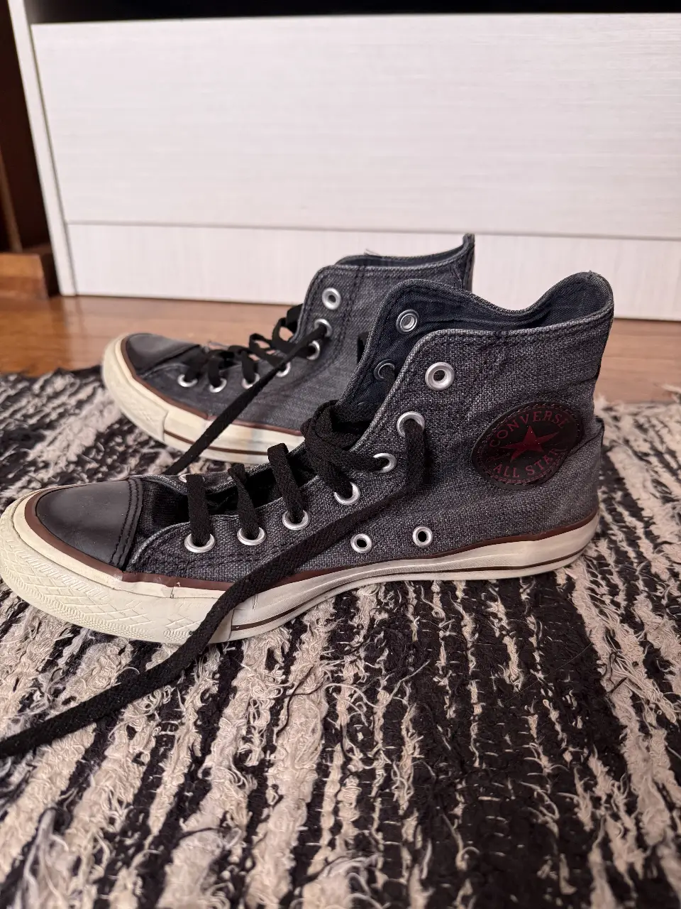 Zapatillas Converse All Star de lona en color gris oscuro con detalles en negro y suela blanca. 