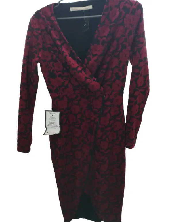 Vestido largo de manga larga con estampado floral en tonos rojos y negros. Diseño cruzado con cierre lateral y escote en V pronunciado. Ideal para eventos o salidas.