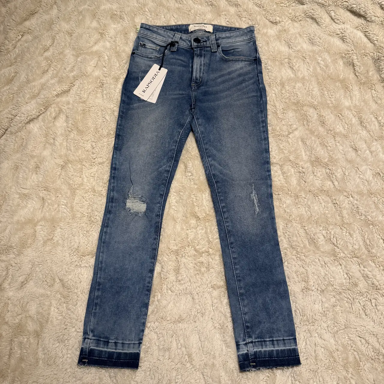 Jeans chupin de mujer, tiro alto, con detalles de roturas y dobladillo desflecado. Marca Rapsodia, talle 24.
