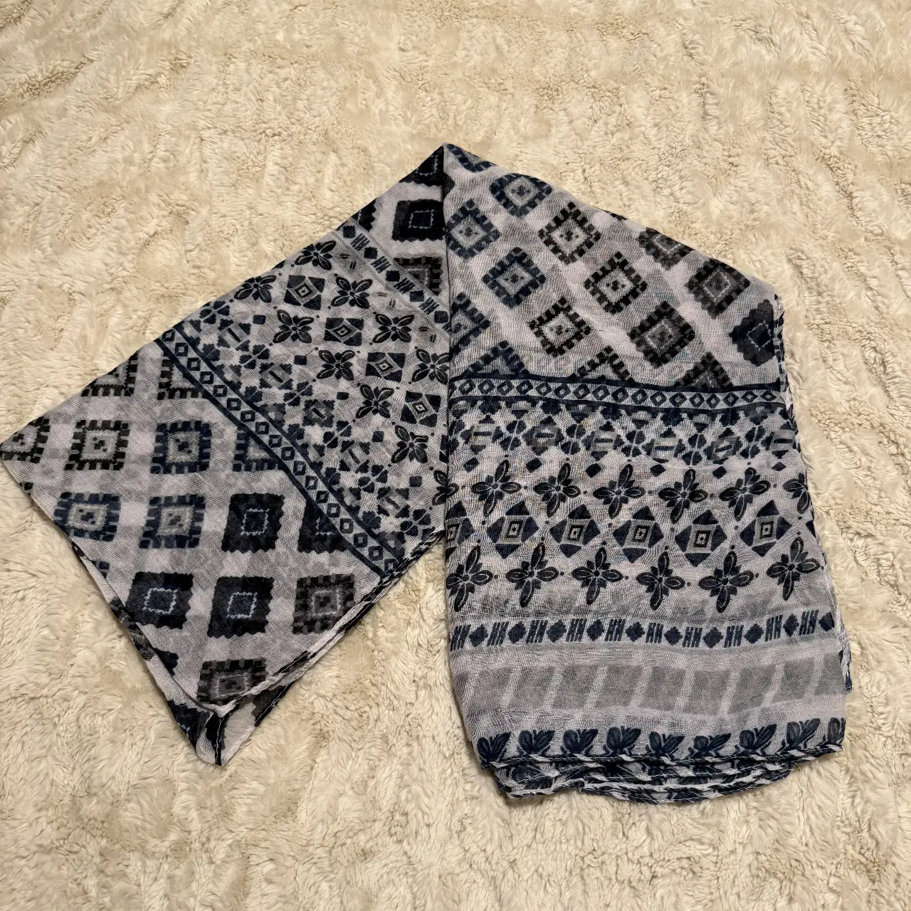 Pañuelo estampado con diseño geométrico en tonos blanco y azul. Ideal para complementar cualquier look.