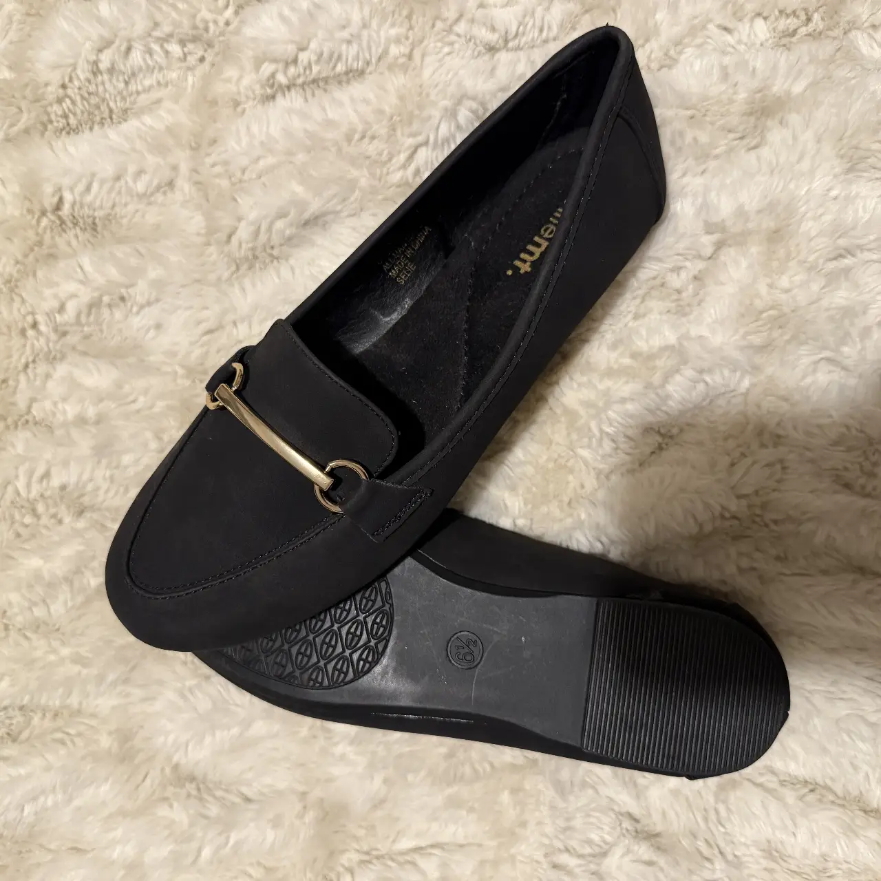 Mocasines negros de mujer, con detalle dorado en la parte delantera. Ideales para un look elegante y cómodo.