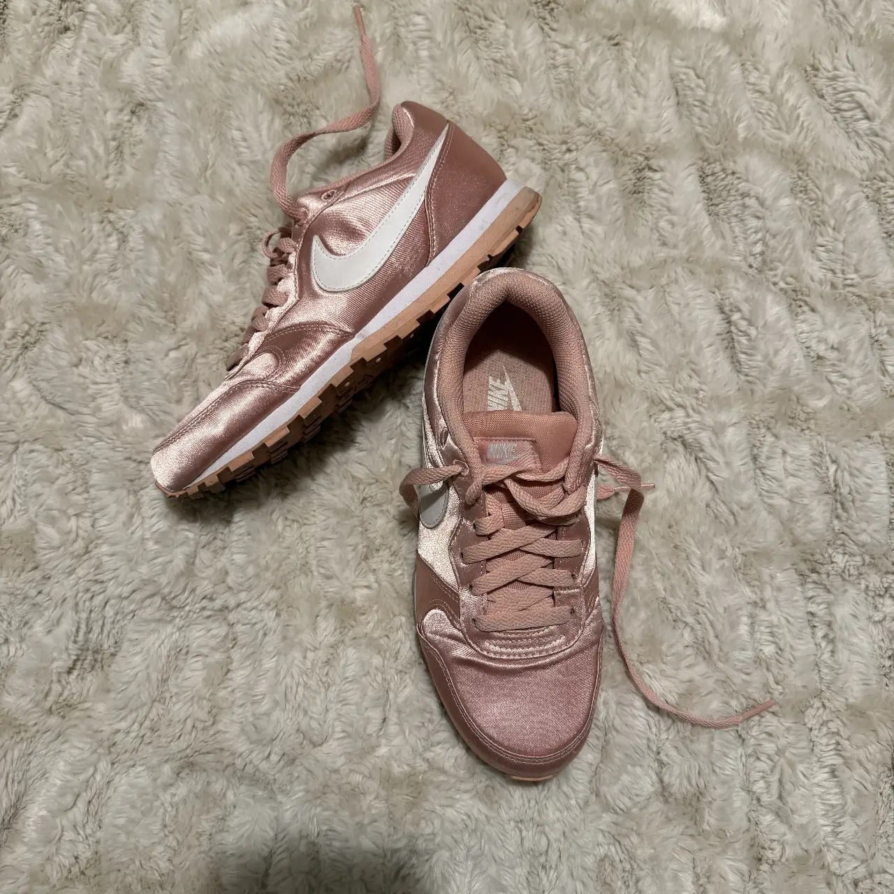 Zapatillas Nike rosas satinadas con detalles en blanco. Ideales para un look casual y femenino.
