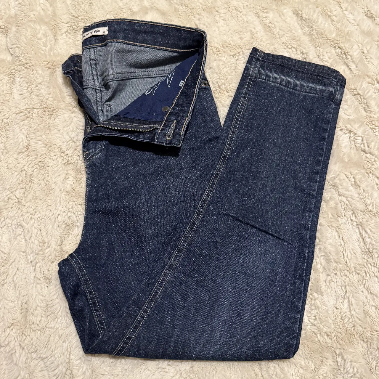 Jeans rectos/mom fit de mujer, color azul oscuro, de la marca Lacoste. Talle 26. Ideal para un look casual y cómodo.