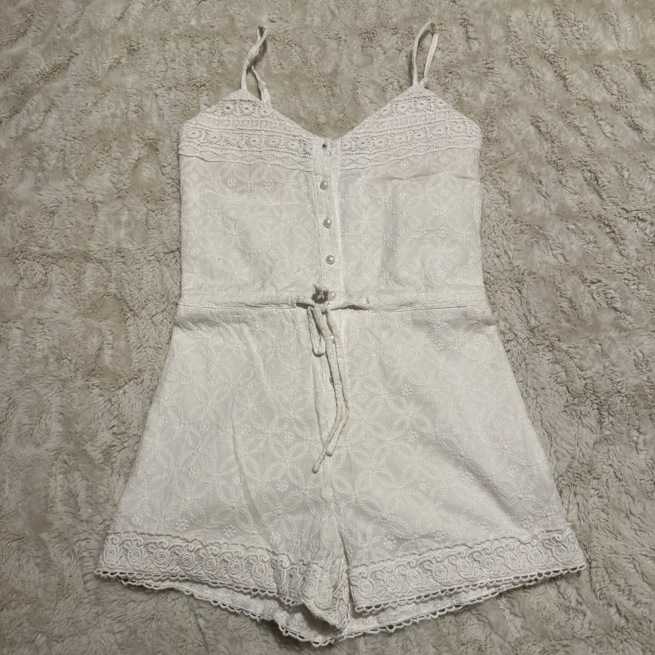 Mono corto blanco con detalles de encaje y botones. Ideal para un look fresco y veraniego.