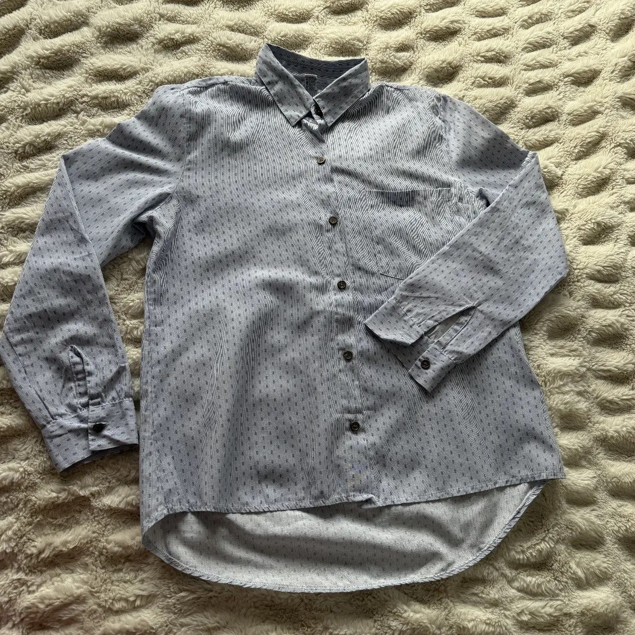Camisa a rayas celeste y blanca, con bolsillo en el pecho y mangas largas. Ideal para un look casual y fresco.