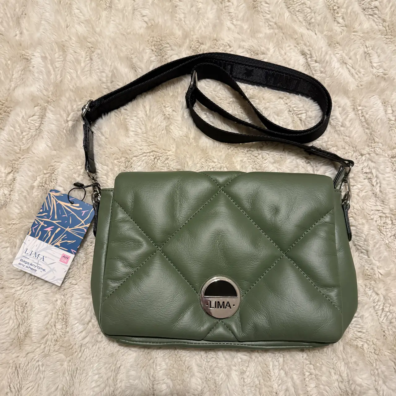 Bandolera de cuero sintético marca LIMA acolchada en color verde, con correa ajustable negra y detalle metálico con el logo de la marca. Ideal para un look casual y moderno.