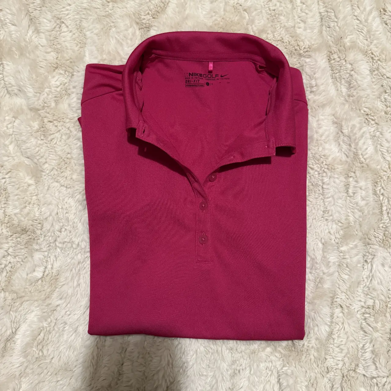 Remera deportiva Nike Golf de mujer, color fucsia, con cuello tipo polo y tres botones. Ideal para actividades deportivas y uso casual.
