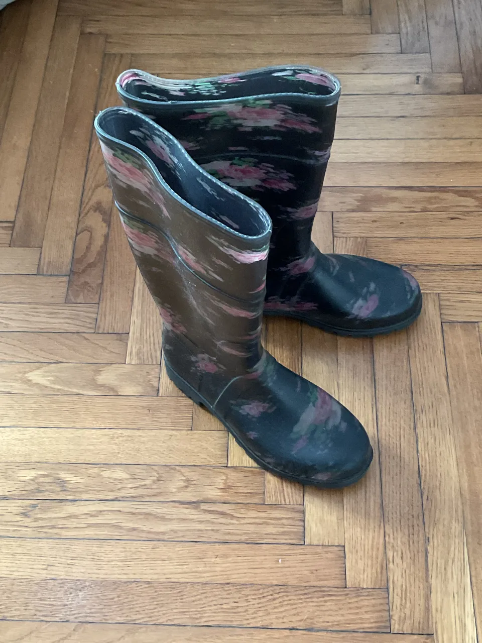 Botas de lluvia negras con estampado floral en tonos rosas y verdes. Ideales para protegerte de la lluvia con estilo.
