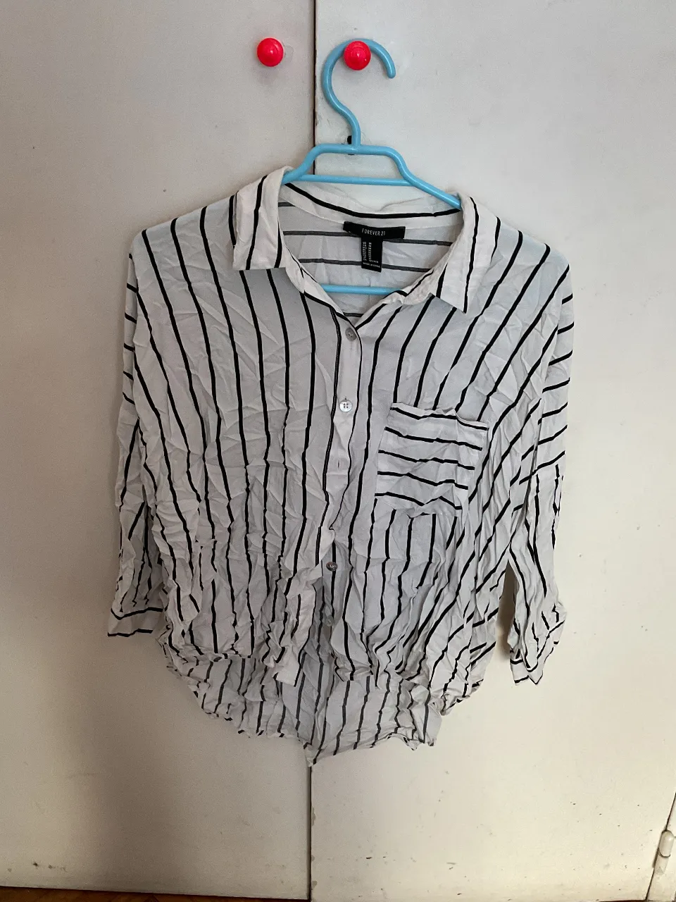 Camisa a rayas verticales en blanco y negro de Forever 21, con bolsillo en el pecho y corte holgado. Ideal para un look casual y fresco.