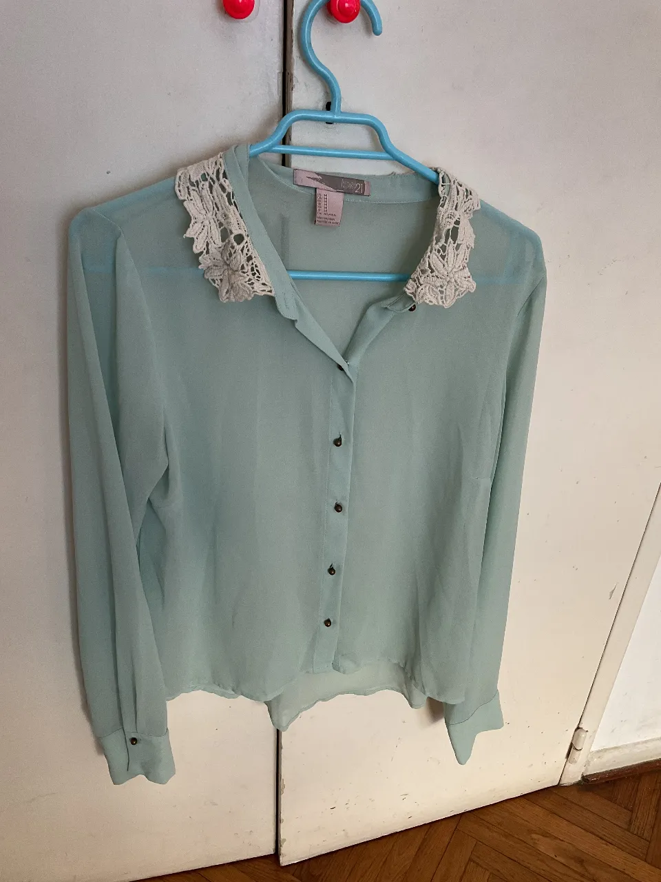 Blusa celeste de gasa con cuello de encaje color crema, manga larga y botones. Ideal para un look elegante y femenino. usada!!