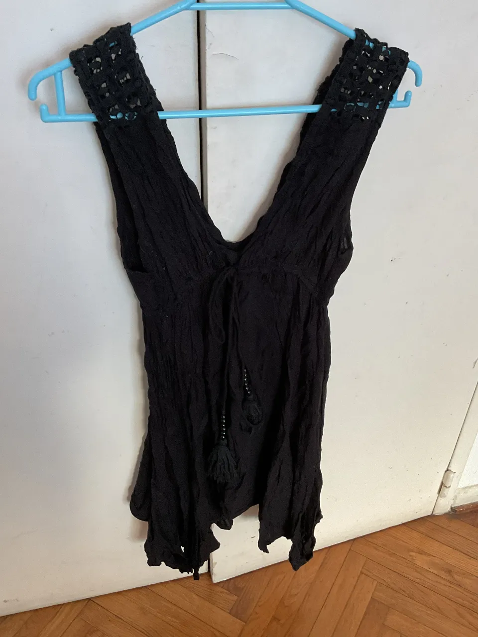 Top negro con escote en V y detalles de encaje en los hombros. Ideal para un look casual y fresco.